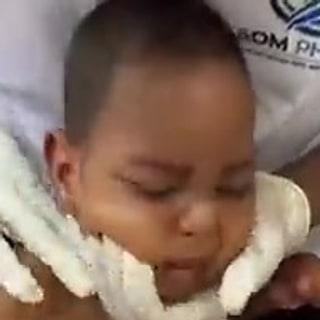 Abdullahi sitzt aufgerichtet, gestützt von seinem Therapeuten